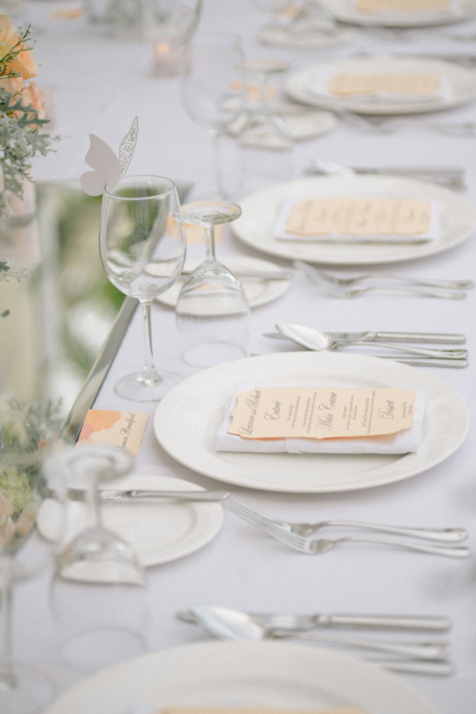 Mesa de comedor formal con cubiertos, menús y centros de mesa florales.