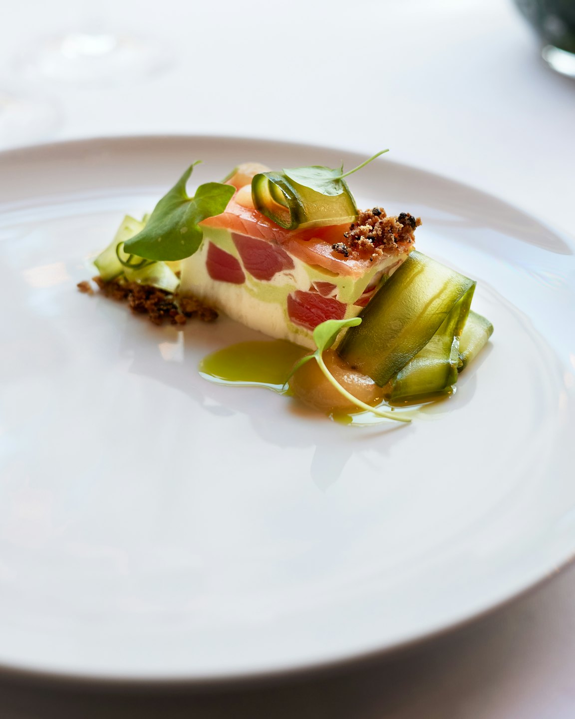 Aperitivo gourmet con cintas de pepino en plato blanco.