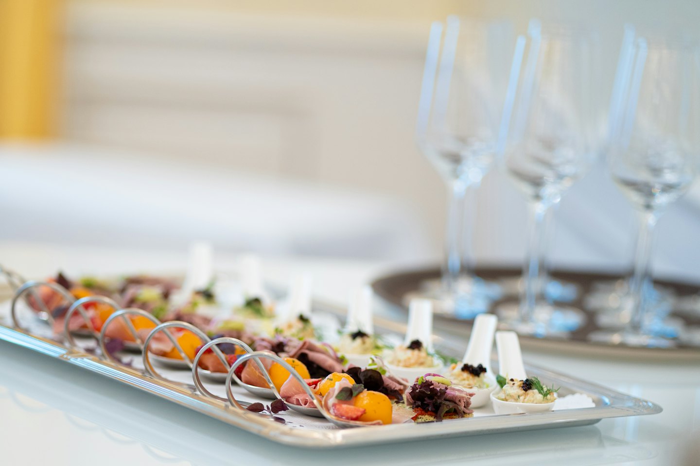 Canapés gourmet servidos en cucharas blancas dispuestas en una bandeja.