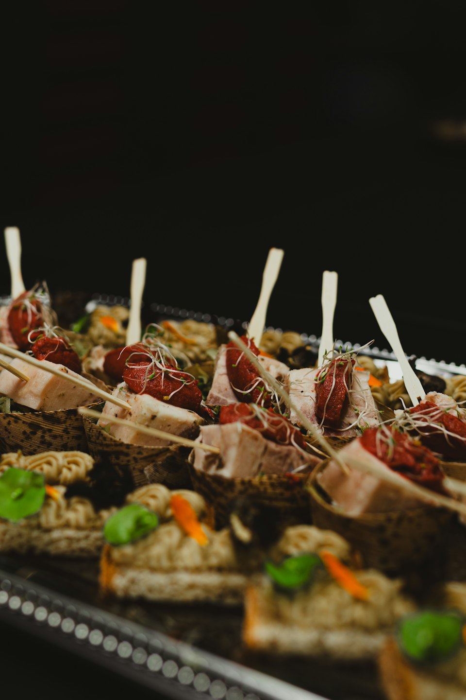 Bandeja plateada de catering con aperitivos gourmet.